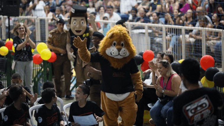 Alunos e mascotes PM Amigo Legal e Dare na cerimônia PROERD no Ginásio Poliesportivo, Extrema, 2025
